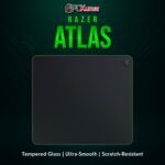 Razer Atlas black tempered glass mouse mat, reflecting ambient light while providing a slick gliding surface for precision.